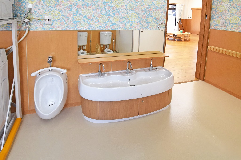 保育室から放射状に配置された幼児用トイレへの見守り動線。保育士の視線が行き届く、安全性と使いやすさを両立した機能的な空間レイアウト