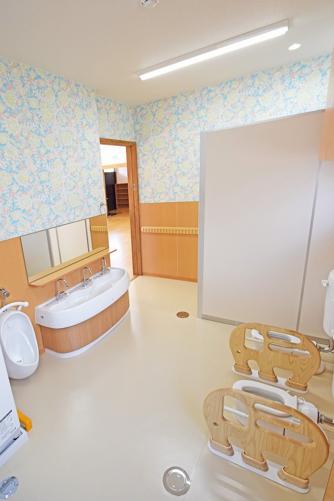 保育室から放射状に配置された幼児用トイレへの見守り動線。保育士の視線が行き届く、安全性と使いやすさを両立した機能的な空間レイアウト